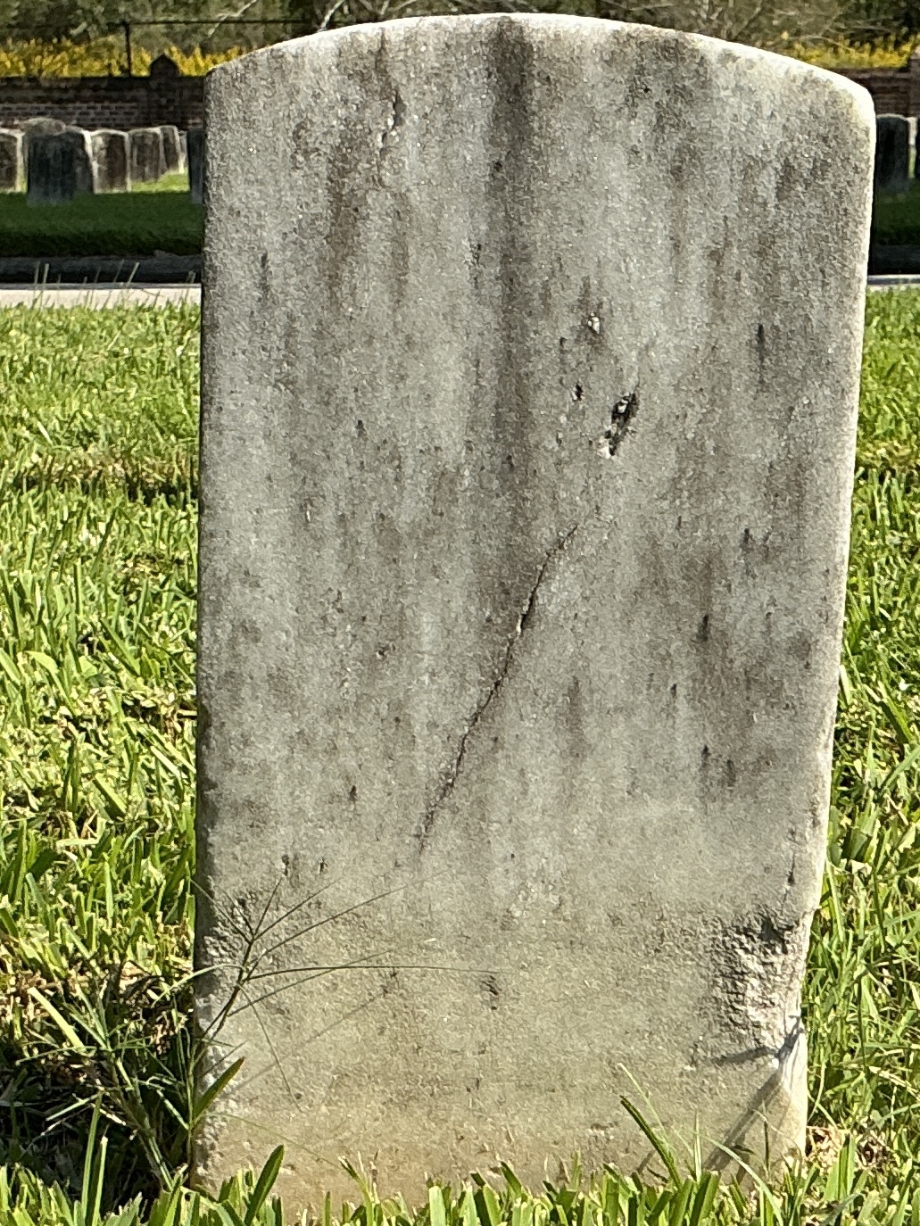 Back of historic upright marble headstone with recessed shield face.