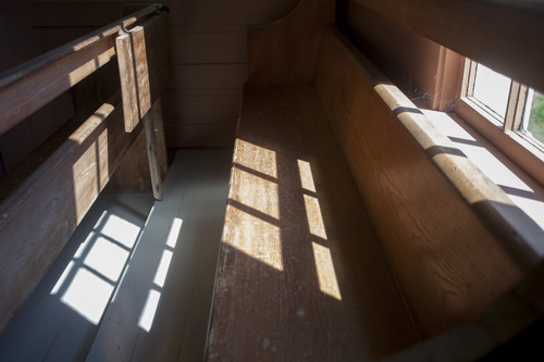 Squares of light fall from a window onto wooden pews.
