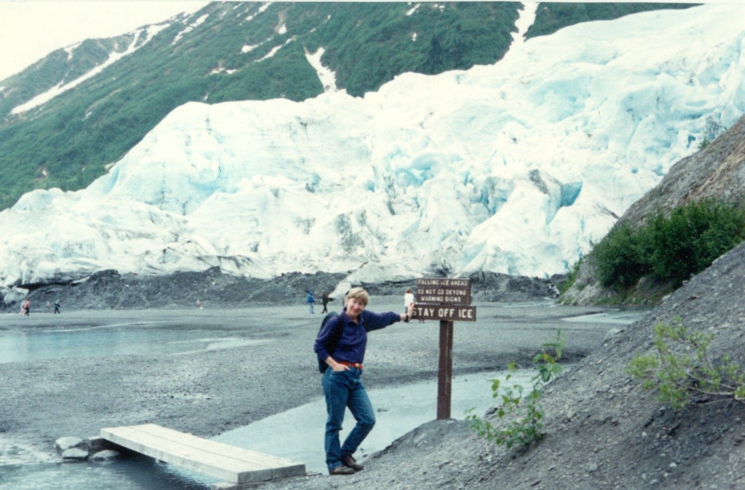 Person poses with sign saying to "STAY OFF ICE" in front of Exit Glacier 1994