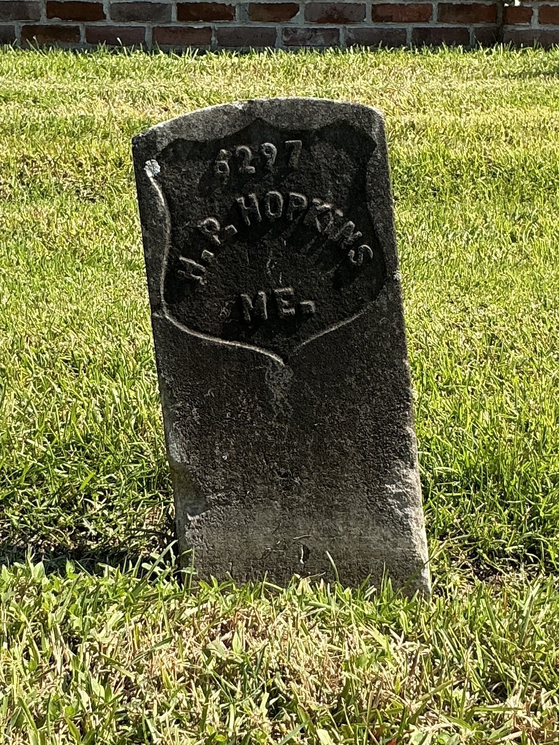 Front of historic upright marble headstone with recessed shield face.