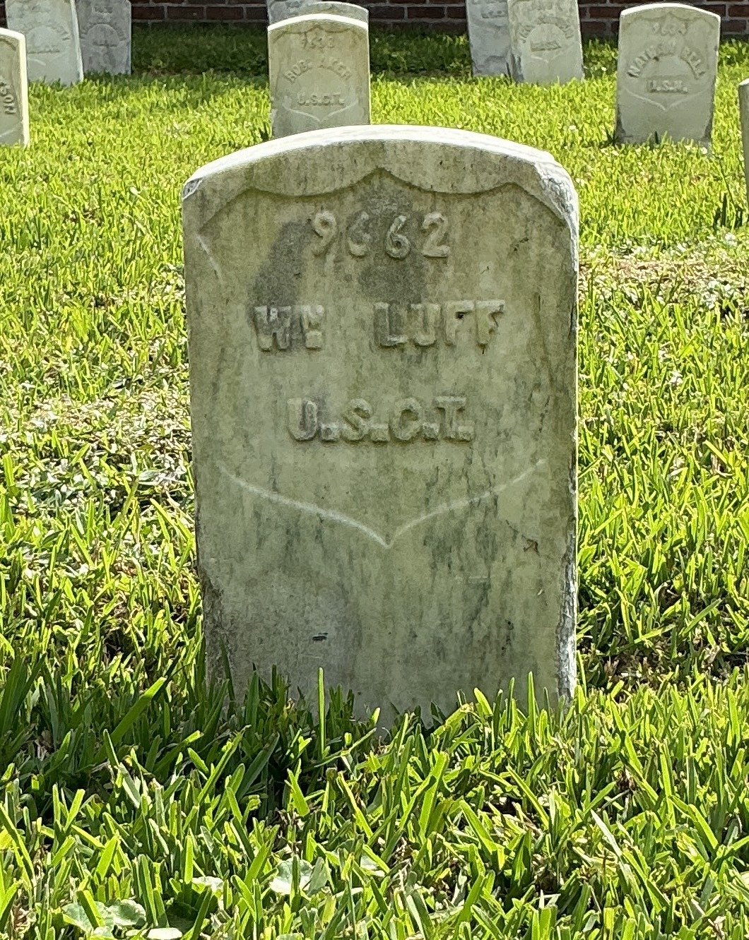 Front of historic upright marble headstone with recessed shield face.