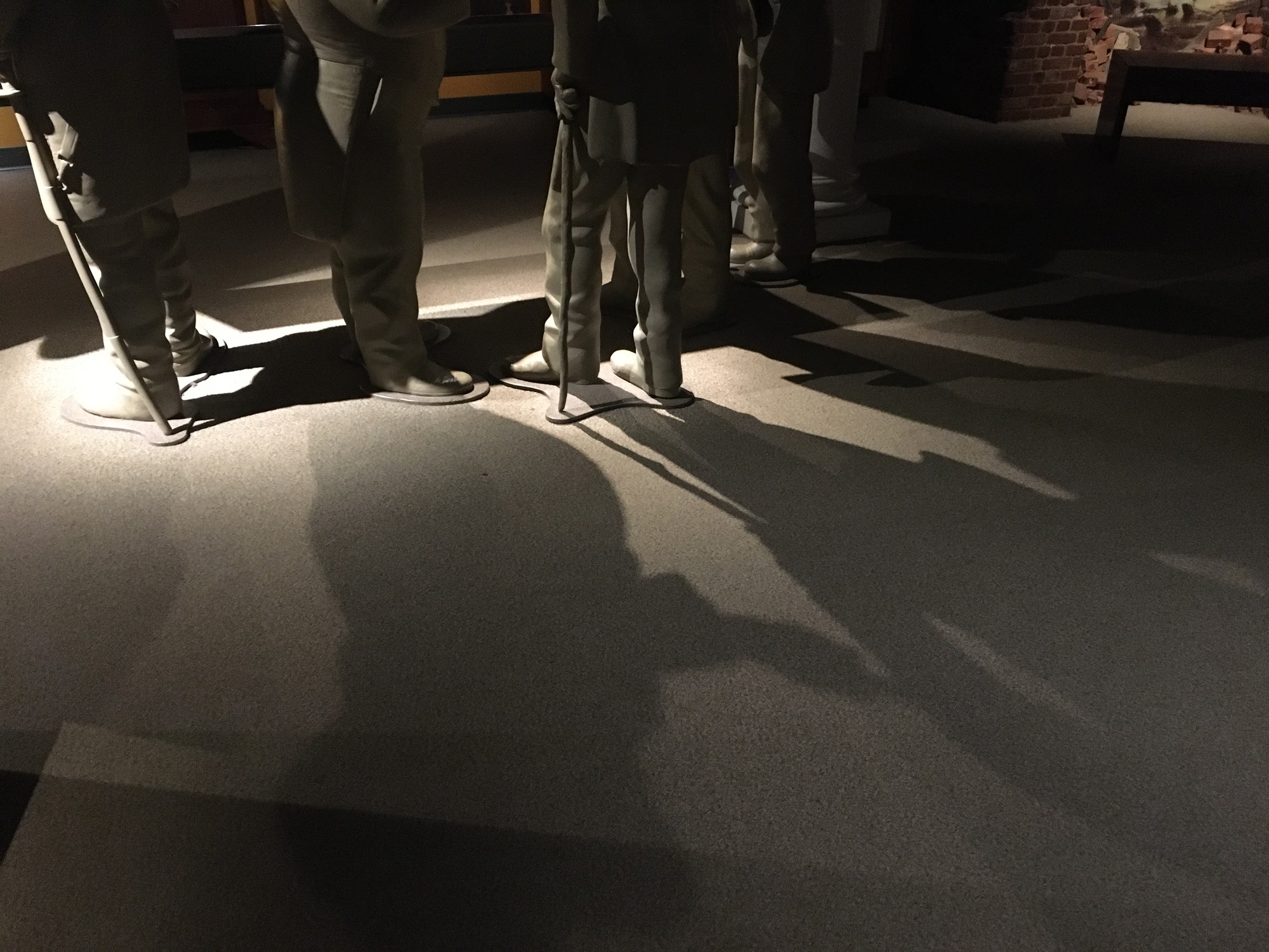 The floor of a museum exhibit with dark shadows cast by exhibit statues