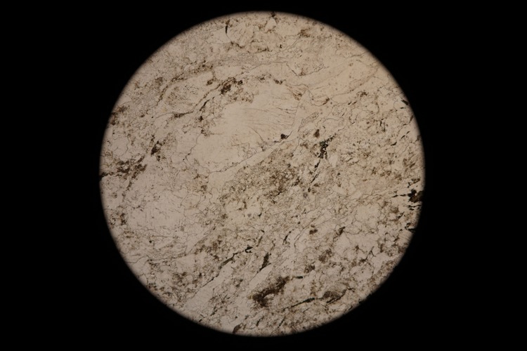 Circular microscopic image of rock structure.