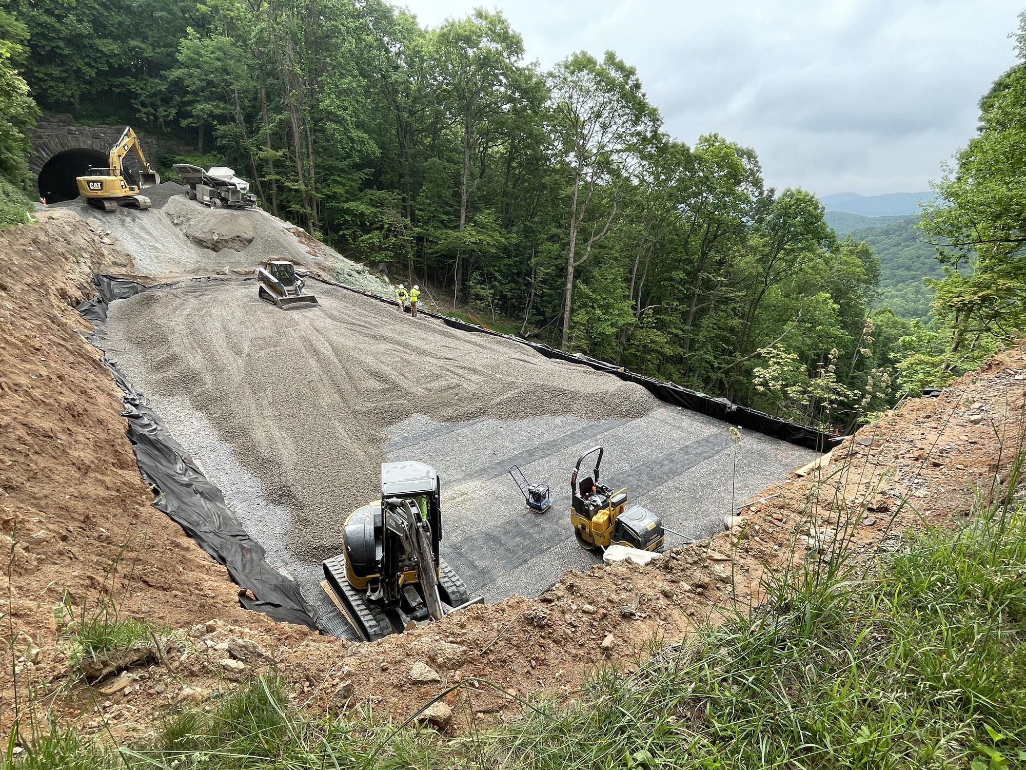 Heavy equipment applies stone over a geotextile barrier as part of the construction process to repair the slope at milepost 401. 