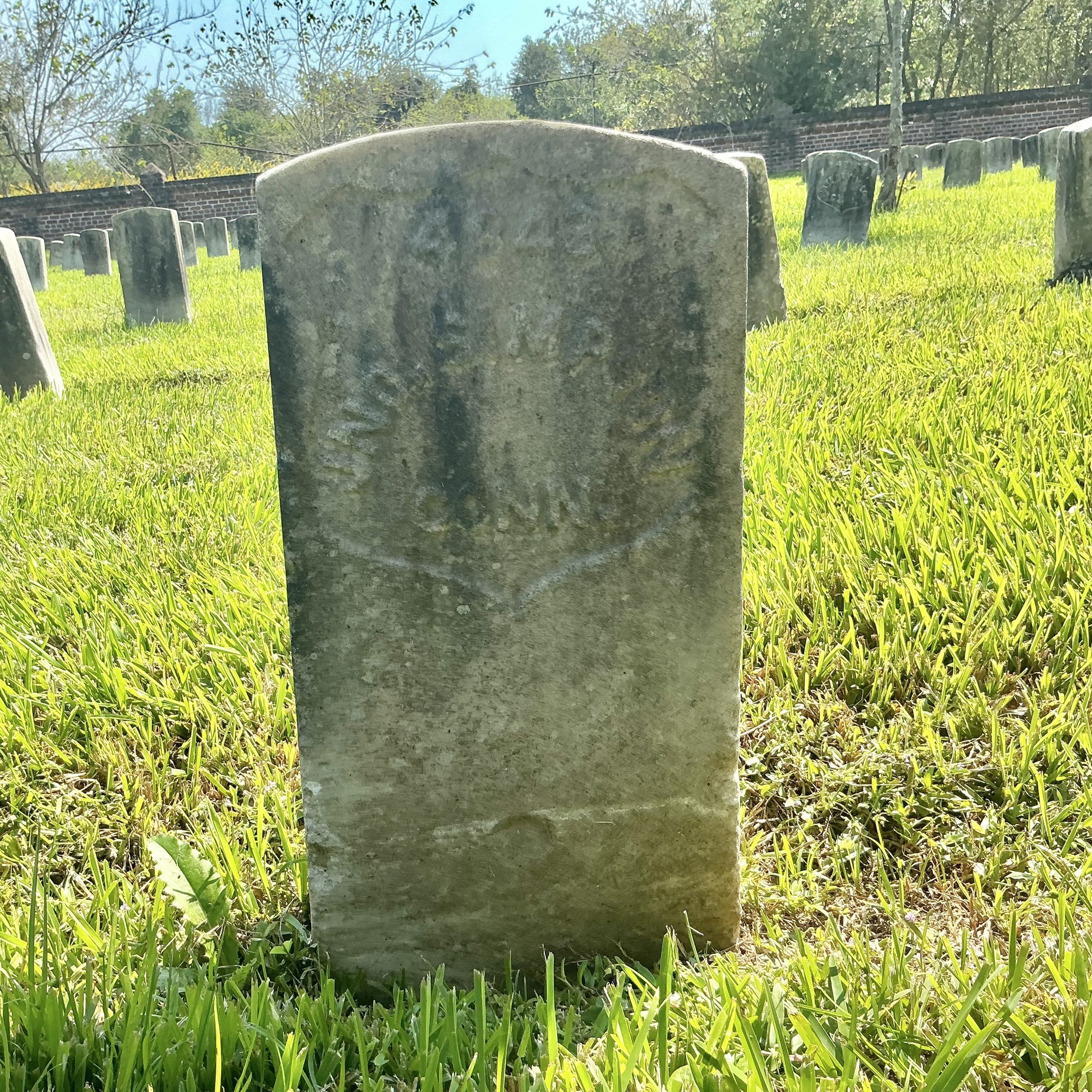 Front of historic upright marble headstone with recessed shield face.
