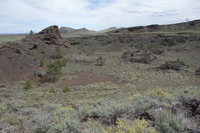 a volcanic crater with a flat sagebrush-covered center surrounded by dark lava rock walls