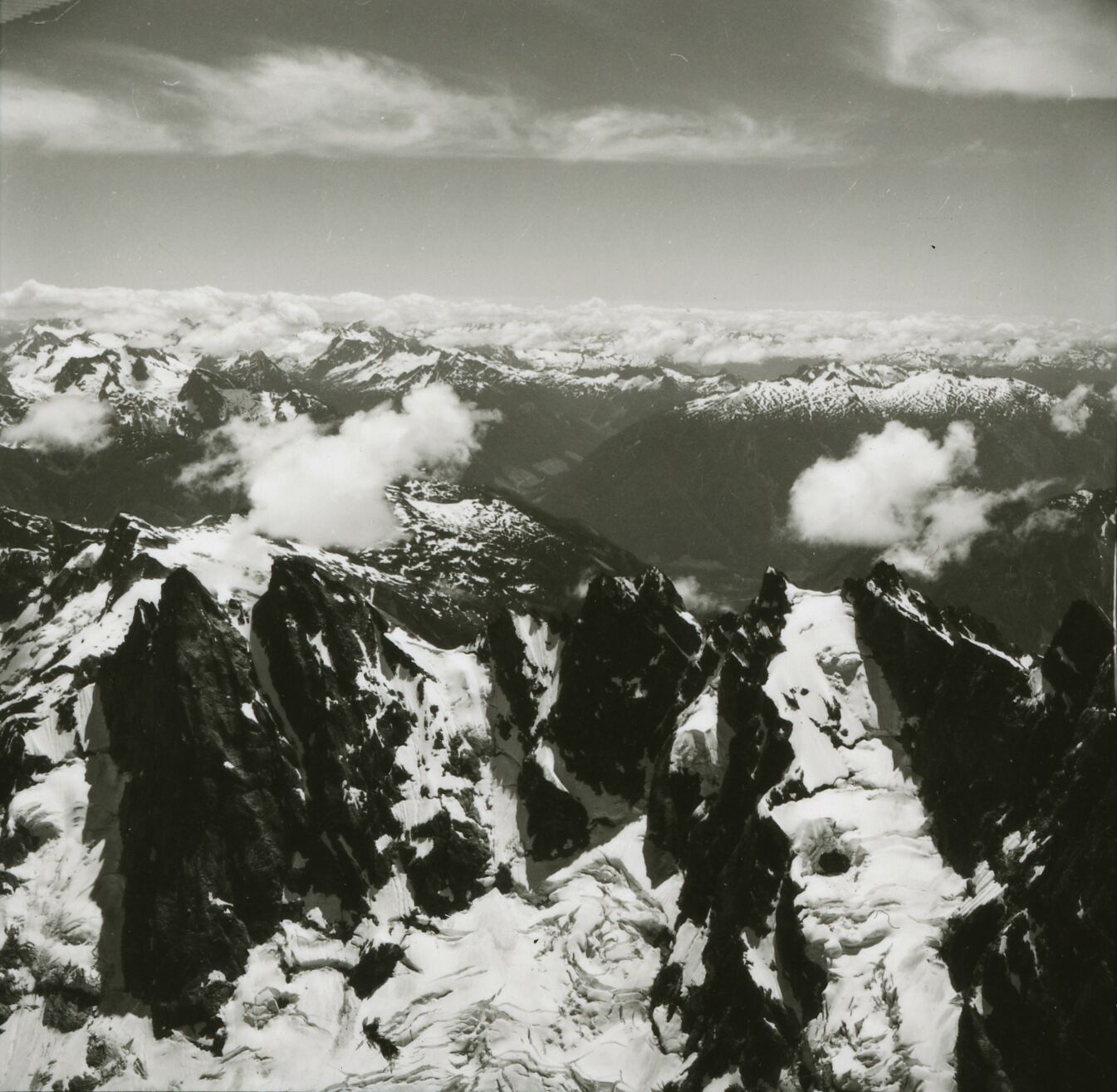 A ridge of steep mountain peaks with many more mountains in the distance.