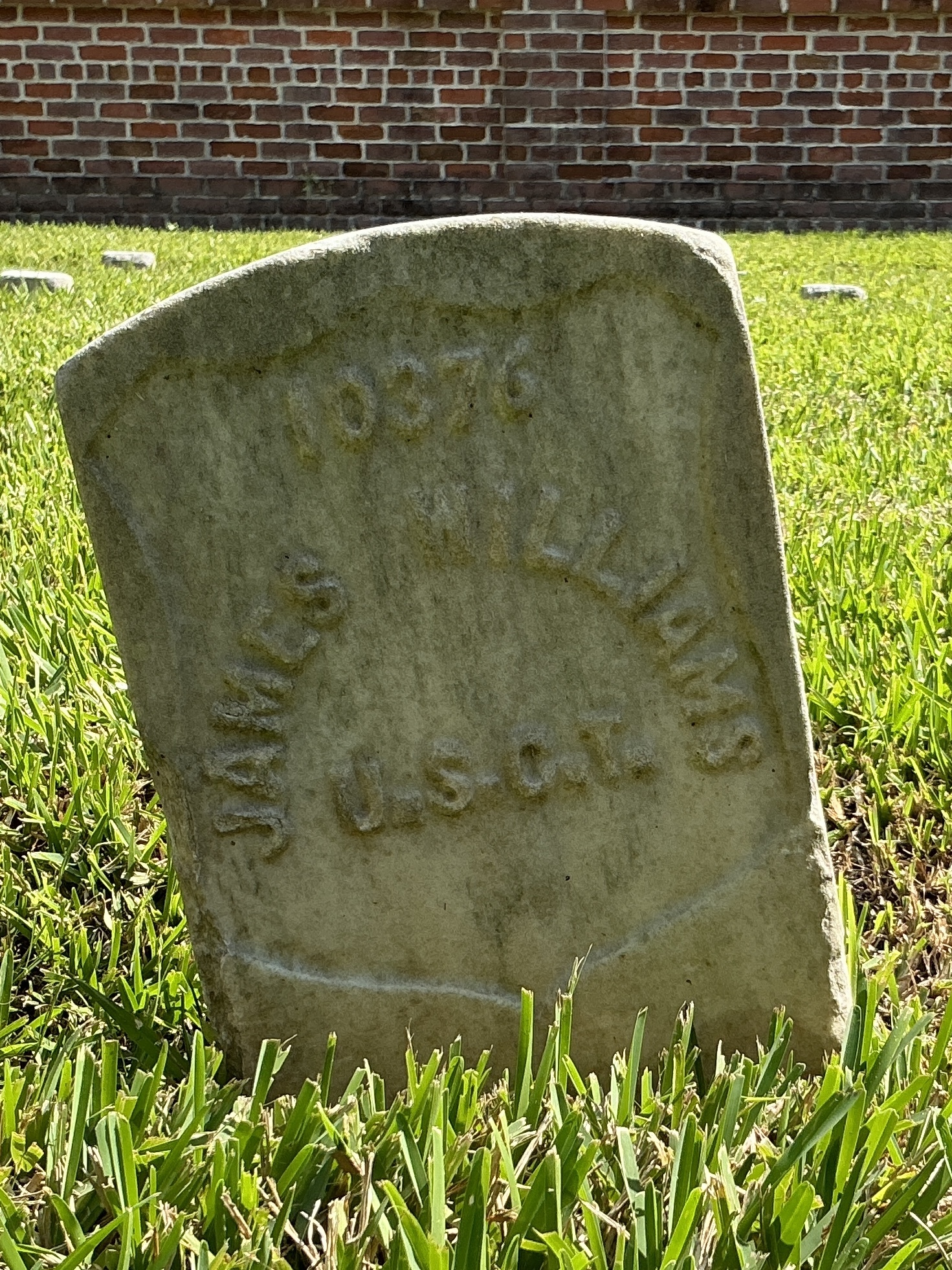 Front of historic upright marble headstone with recessed shield with recessed lettering face.