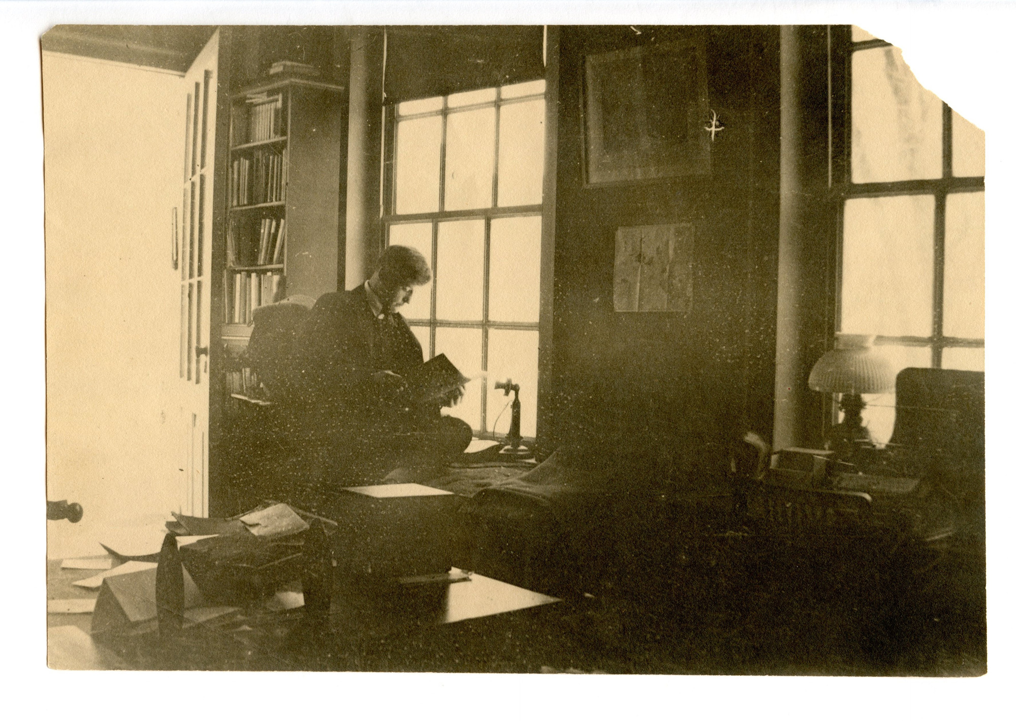 Young man sitting in front of window reading.