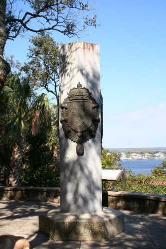 stone column with French heraldry and river in distance. 