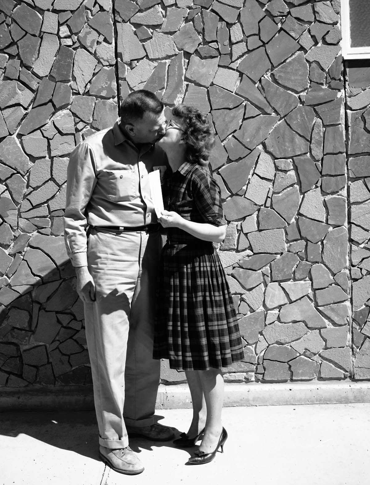 Dorothy Wilmes, mail and files clerk, kisses her husband Ray, Buildings and Utilities foreman, after she was awarded $25 Incentive Award from Acting Superintendent Robert Peterson.