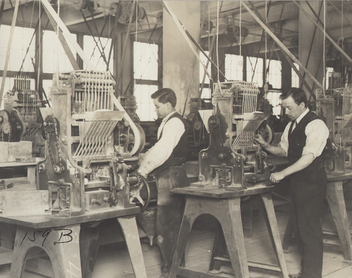 Workers operating machine for Edison storage battery production.