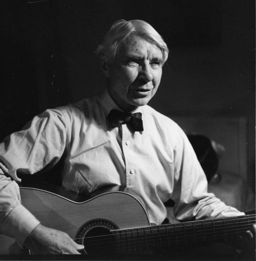Carl Sandburg with his guitar singing folksongs after an evening of poetry.