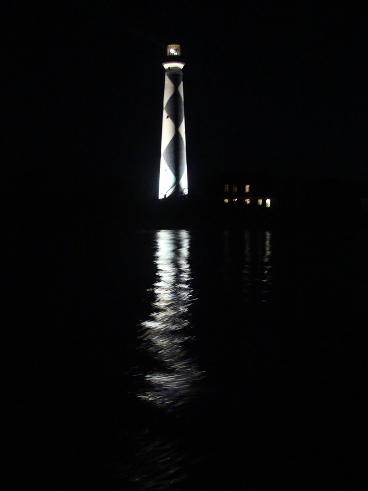 Cape Lookout Lighthouse reflected in the water at night.