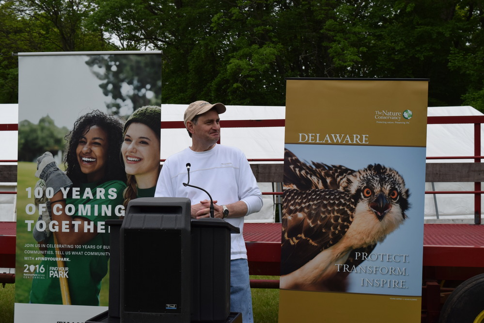 A man stands at a podium and greets the crowd. 