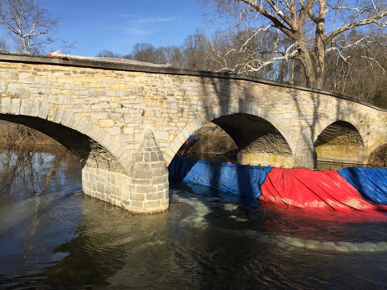 A damn prevents water from flowing through one arch so workers can re-point and rehab the east pier.