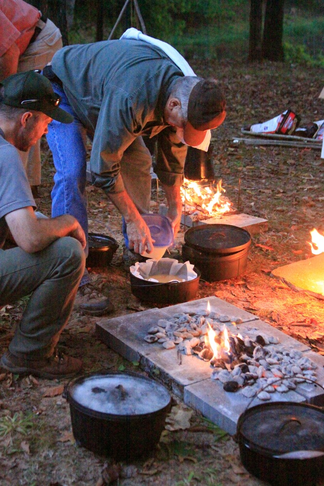 Park VIP Lynn LaBudde prepares breakfast using a dutch oven as VIP Coordinator Dave Thomas looks on.