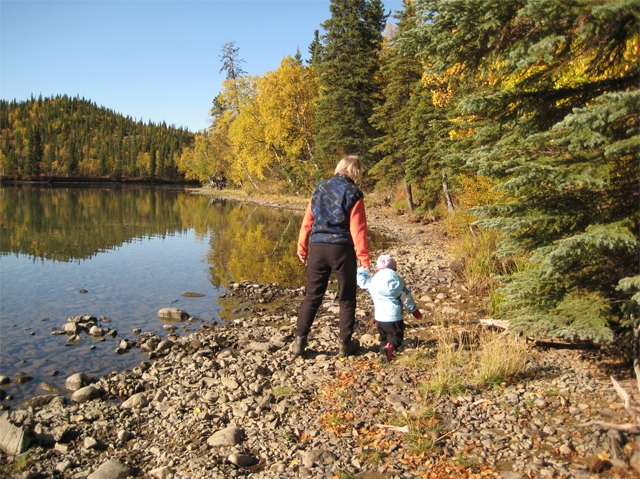 woman walking with a boy along a forested lakeside