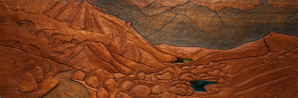 wood carving of a mountain landscape with small mirrors representing lakes
