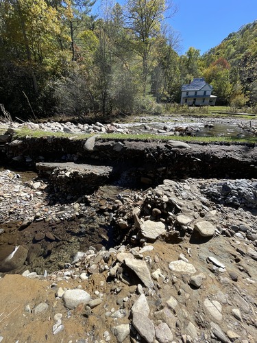 Creek is in background. Road in foreground. Creek is higher than road. 