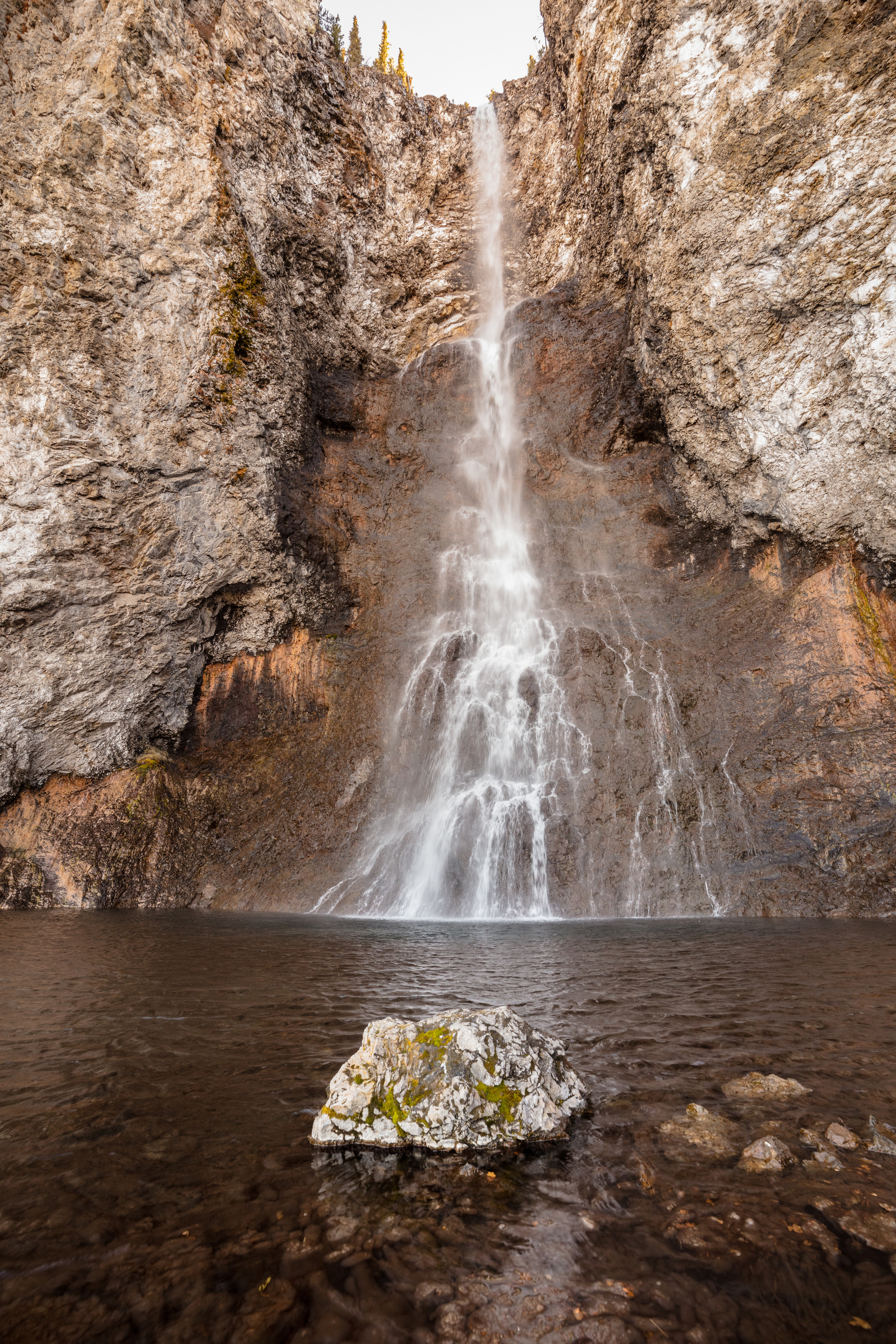Water drops over a cliff into a pool