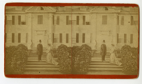 Man and a woman stand in front of Georgian mansion.
