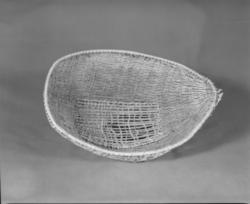 Private Collection. Object: Miwok winnower. Dimensions: 13 1/2 x 10 x 3 1/4". Materials: Willow shoots, unidentified split shoot possibly ceanothus sp., Rimstick also probably Ceanothus. Technology: Diagonally twined up to right slant of turns, one third of way from start alternate rows begin. One row of three strand twining at ends selvage of basket. Repair of missing central portion of basket done in split willow shoots (?) and scraped willow shoots (?) and sewn to basket. Collection History: Purchased at Three Flags Trading Post, Coleville, CA with Miwok label. Photographed by Michael Dixon. Catalogued by Craig Bates and Barbara Beroza. Yosemite Collections, National Park Service.