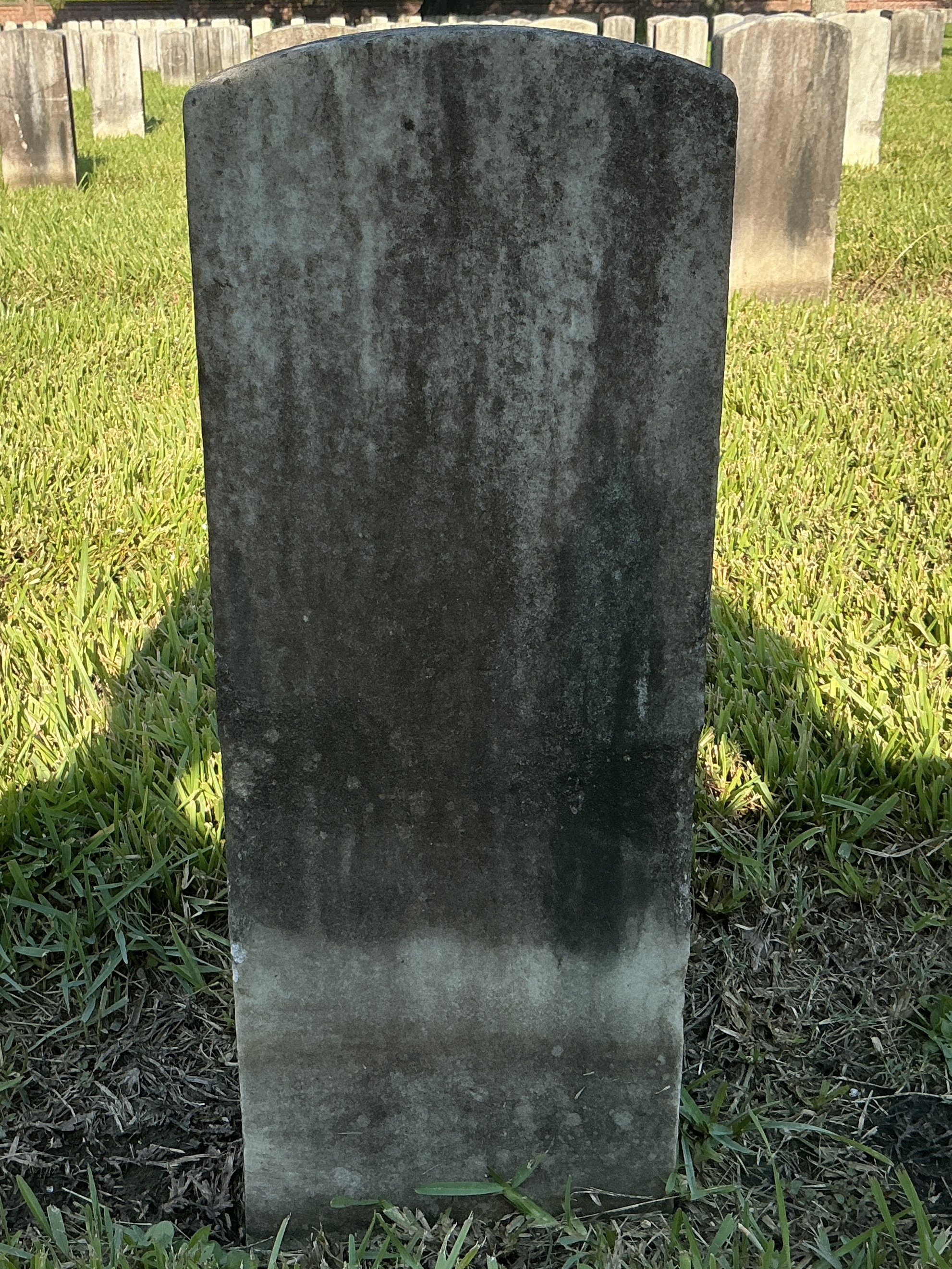 Back of historic upright marble headstone with recessed shield face.