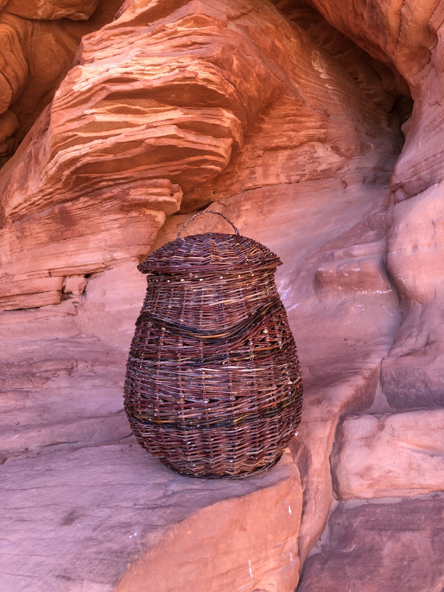 An oval-shaped wicker basket sits on a red sandstone ledge.