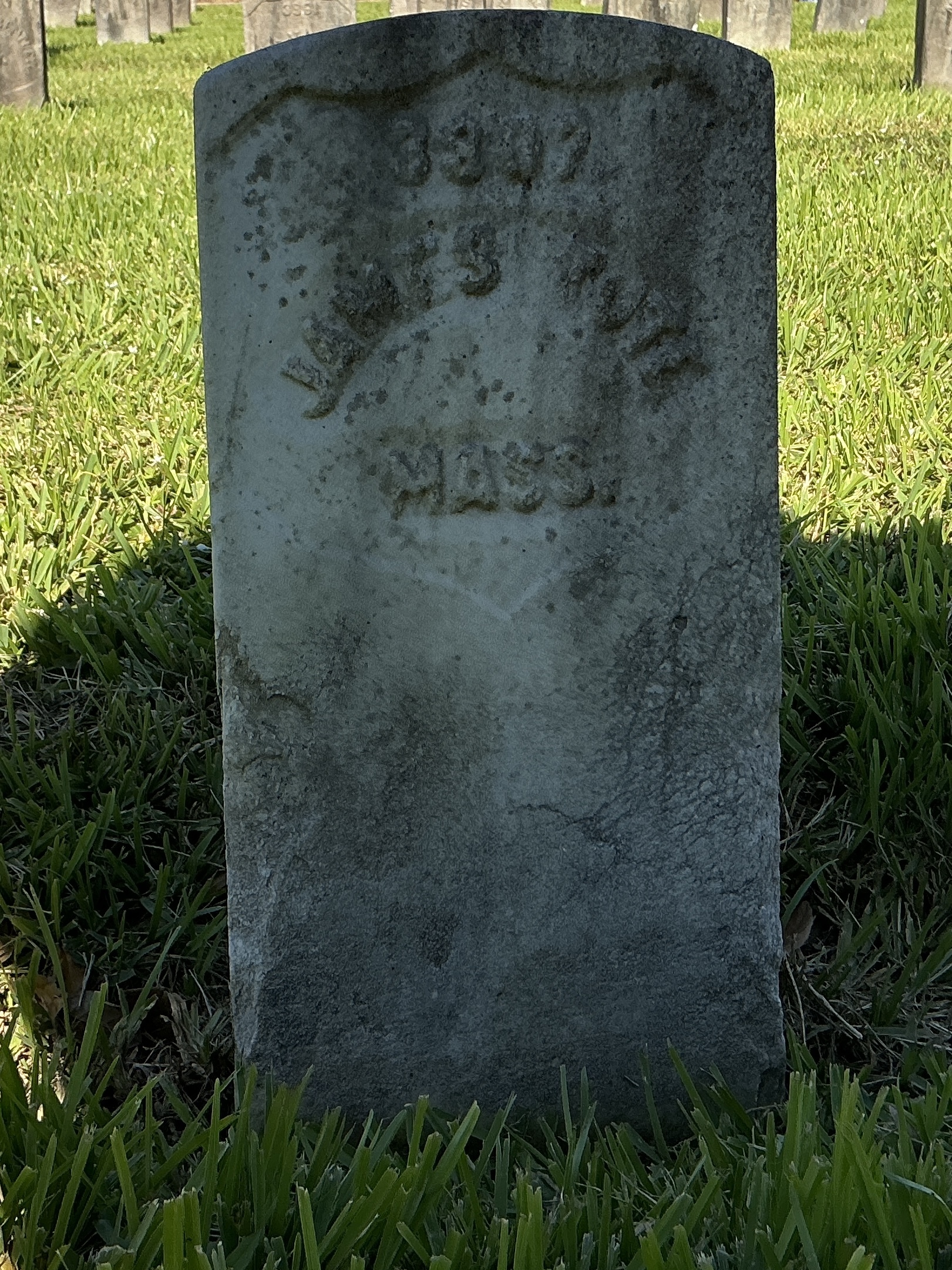 Front of historic upright marble headstone with recessed shield with recessed lettering face.