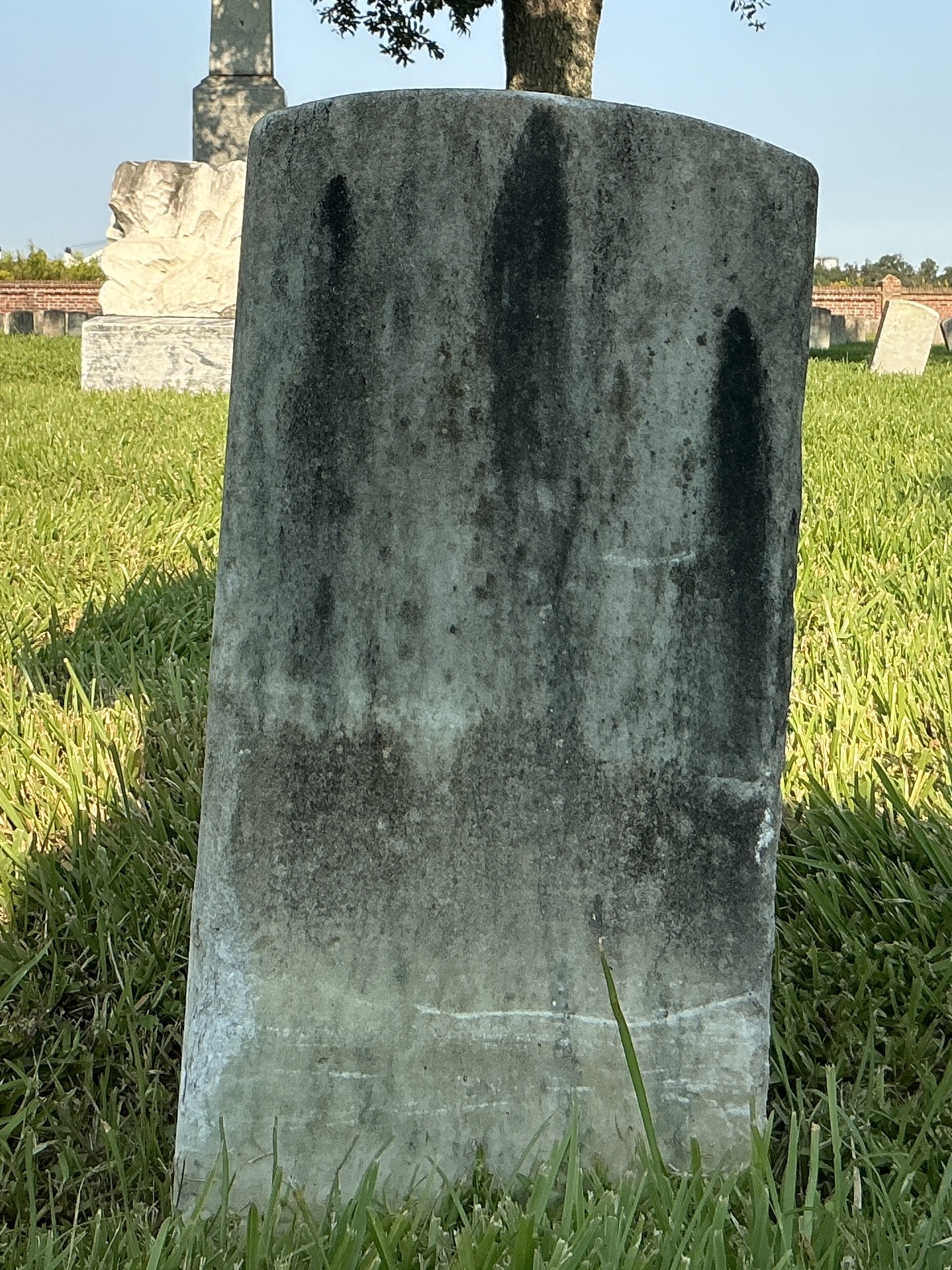 Back of historic upright marble headstone with recessed shield face.
