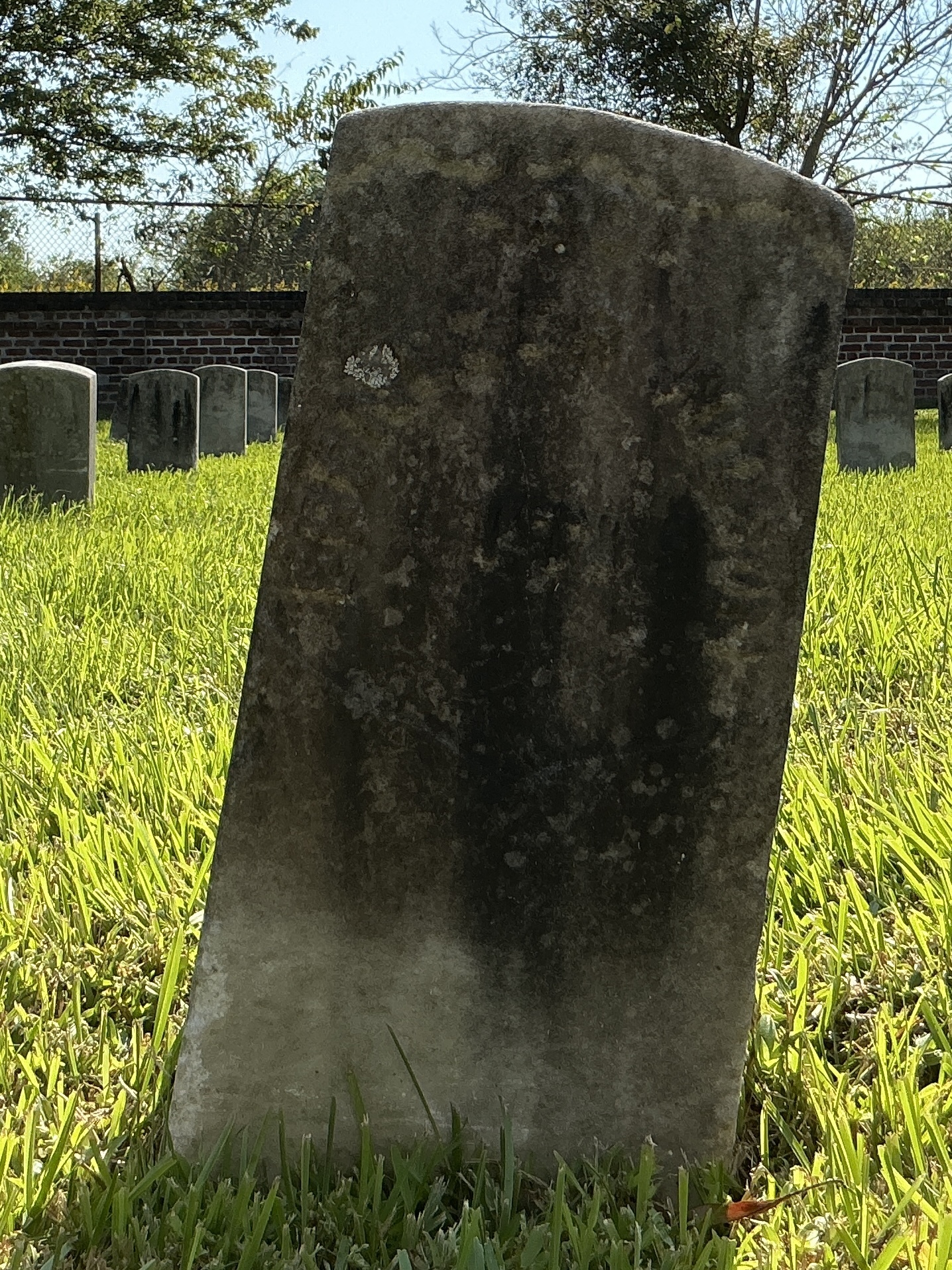Front of historic upright marble headstone with recessed shield face.