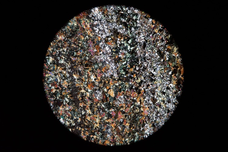 Circular microscopic image of rock structure.