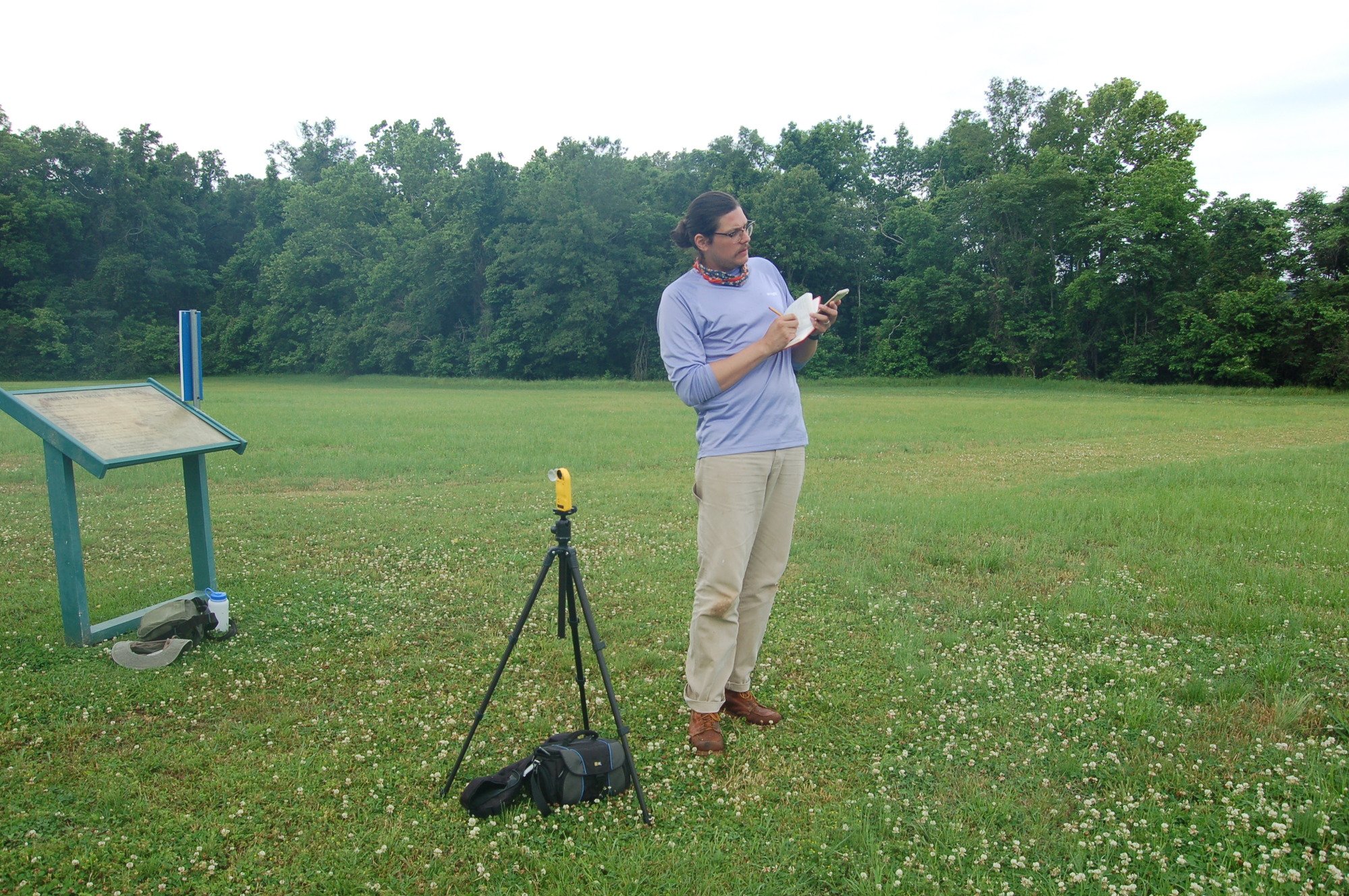 A man taking notes in a field.