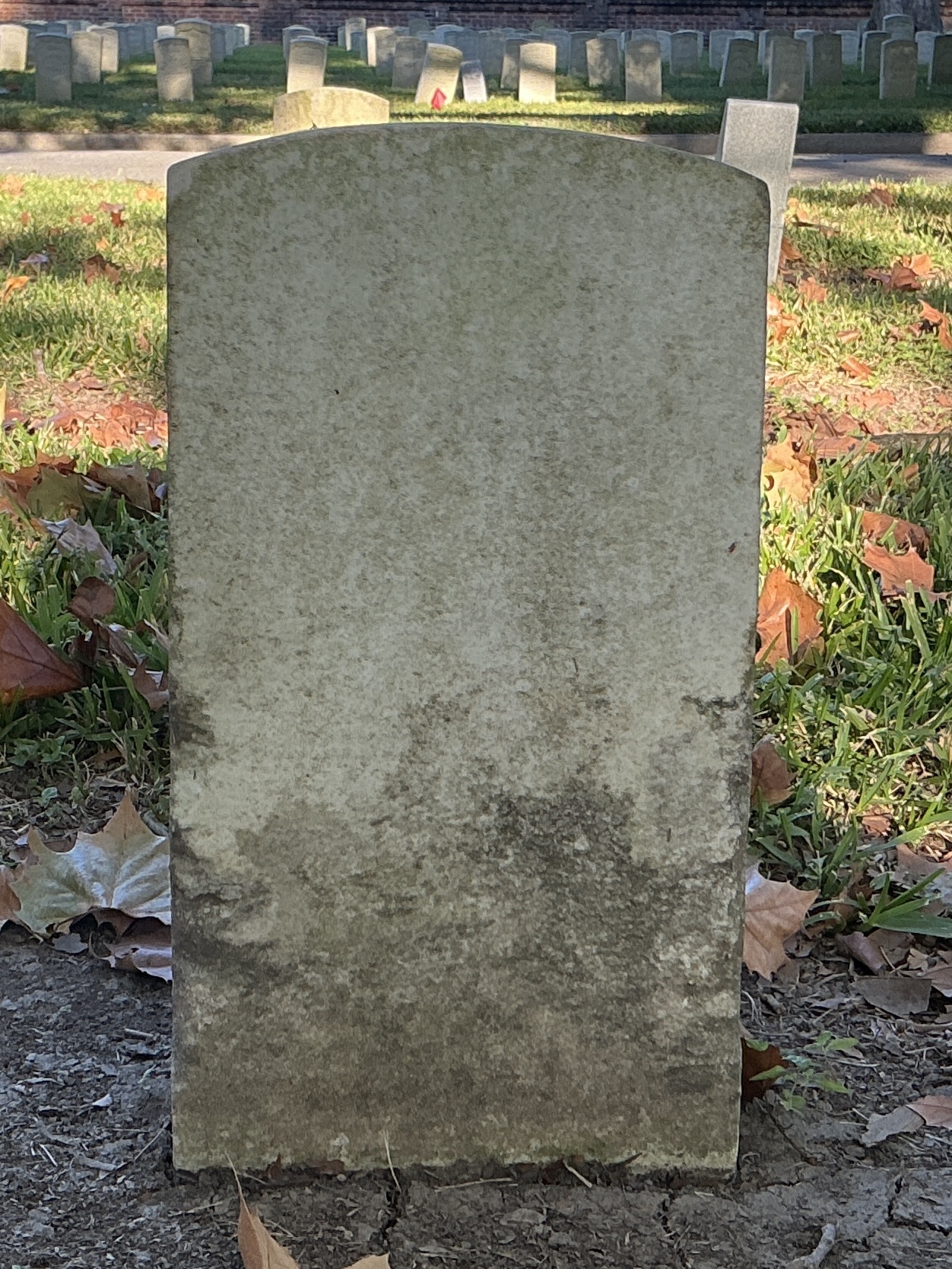 Back of historic upright marble headstone with recessed shield face.