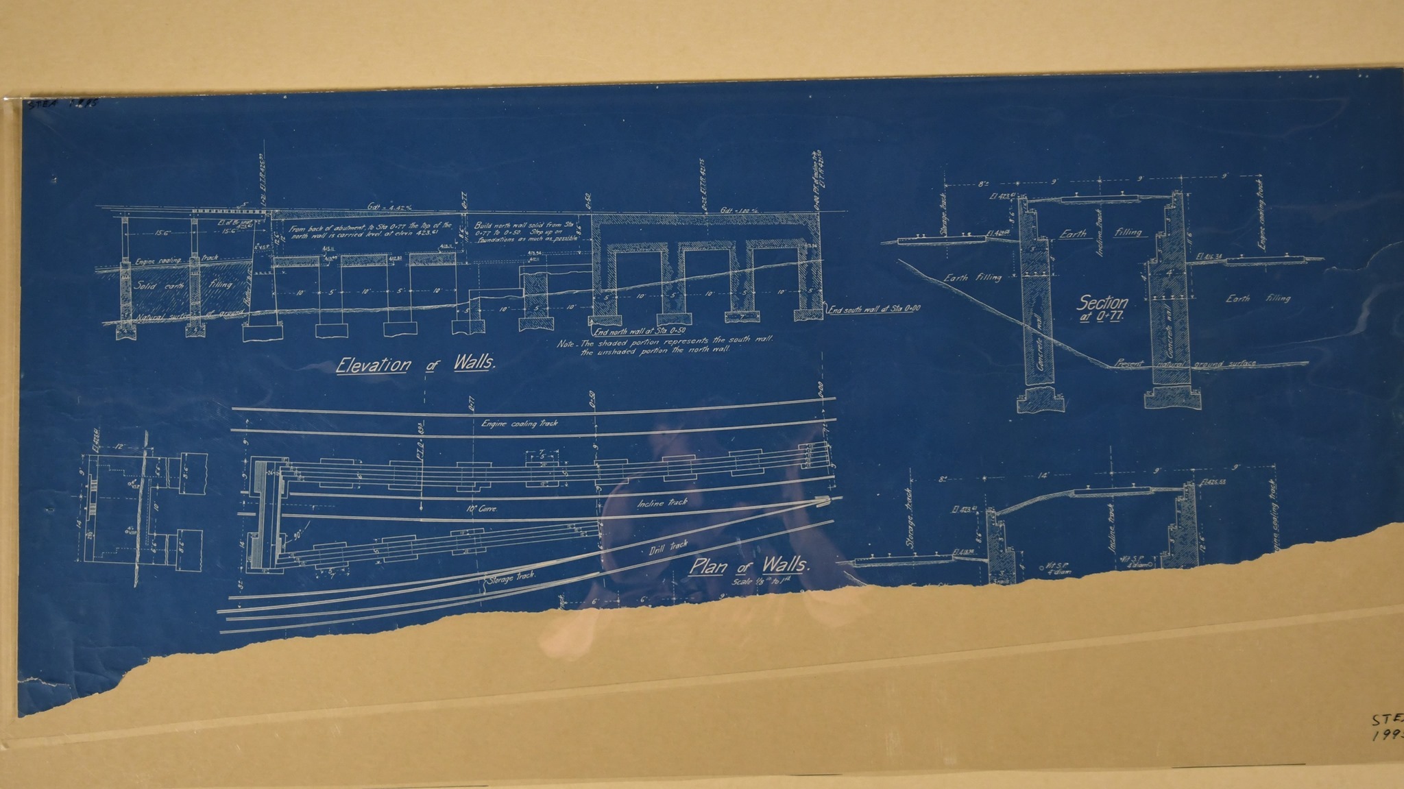 Blueprint diagrams of coaling dock/trestle, DL&W Railroad yard, Scranton, 1900-1906. "Elevation of Walls," "Plan of Walls," "Section at 0+77." Diagram of first 128 ft. of structure. Shows relationship to engine coaling, drill, storage tracks. Details of construction, specifications of concrete foundation walls. 