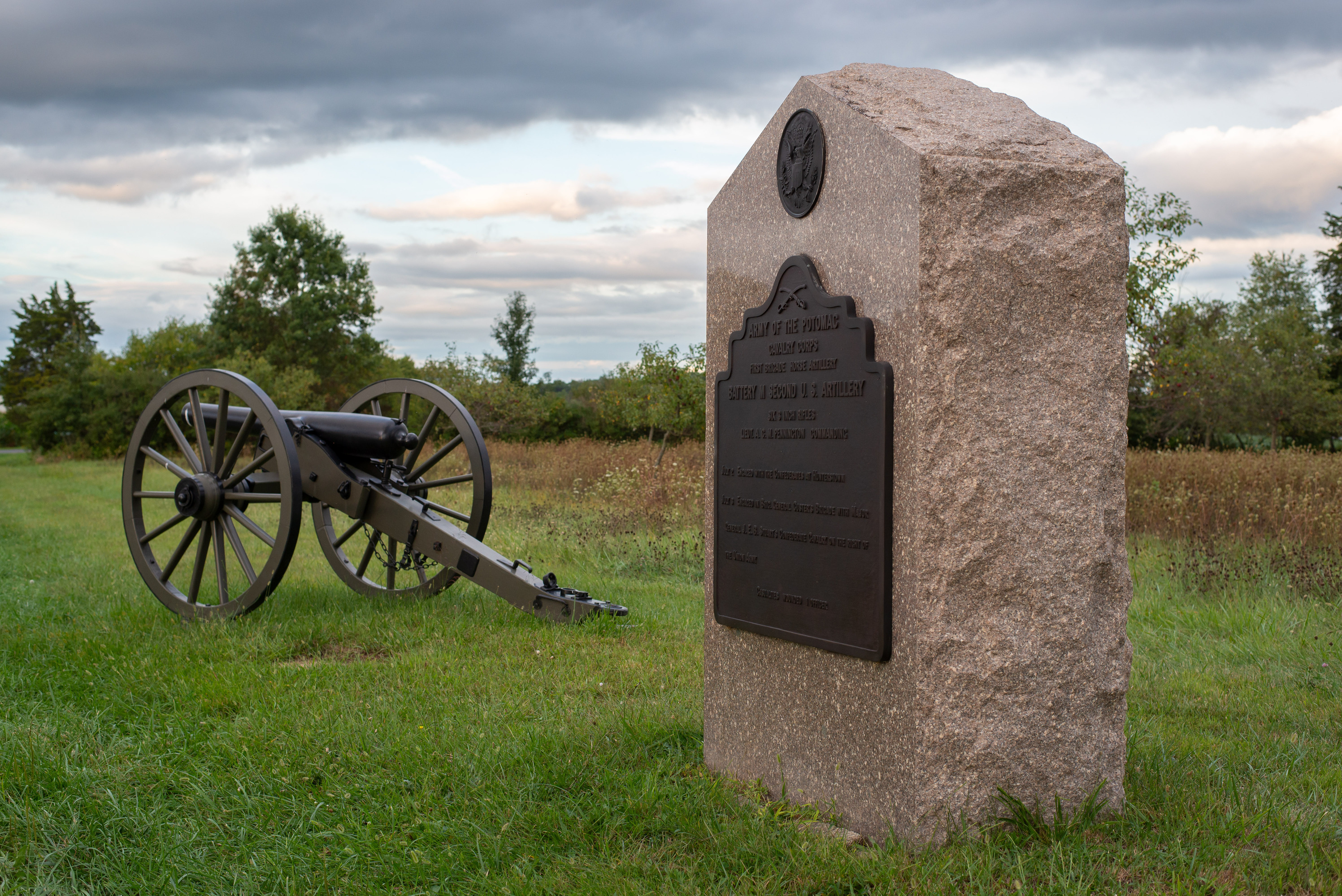 A cannon and a historical marker next to a road.