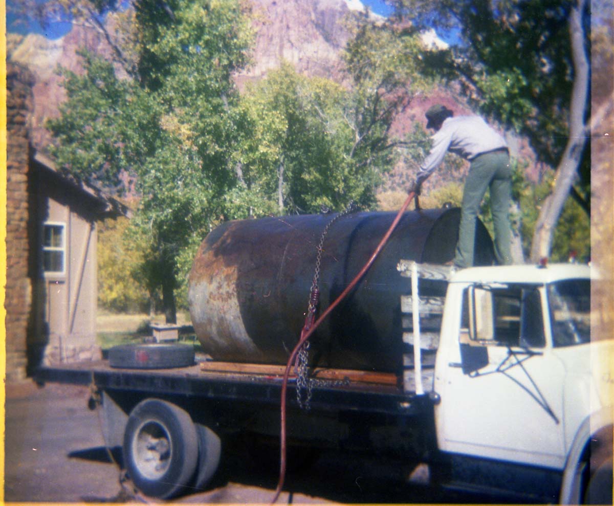 Color Photos of Park Service trucks. Man standing on roof of truck to put hose into tank, tank is loaded on trailer.