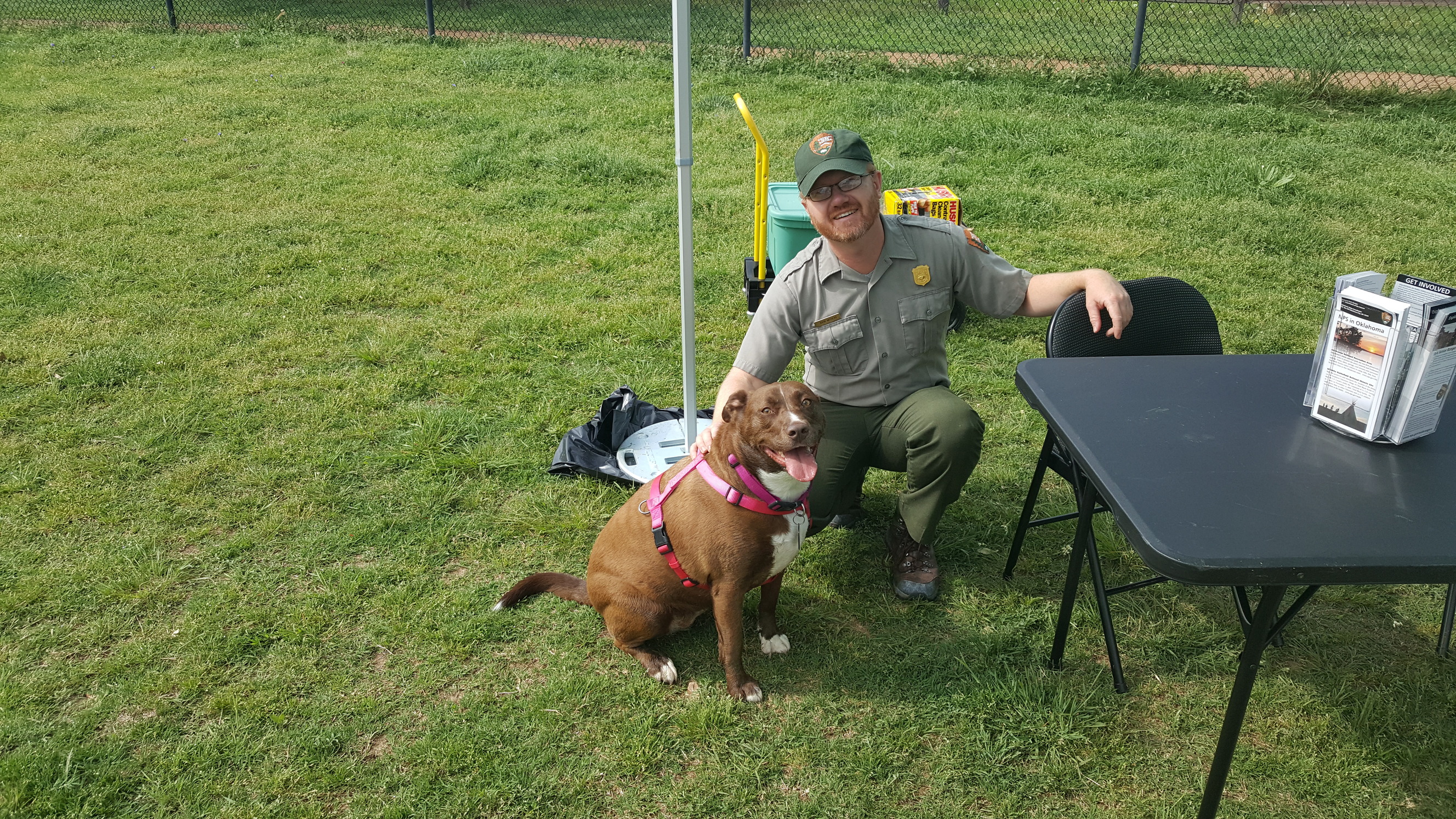 A park ranger with a brown dog