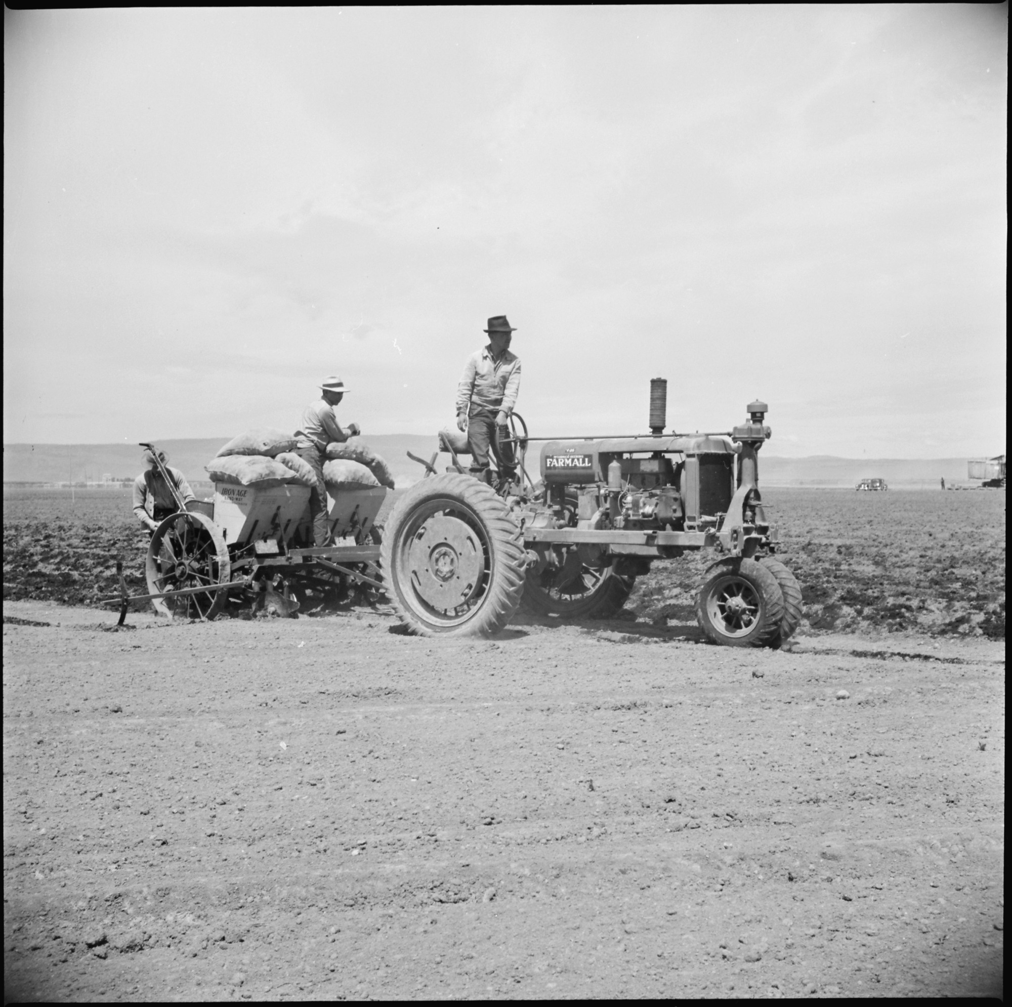 A crew of evacuee-farmers planting potatoes with a semi-automatic-feeding, rotary potato planter on the project farm at this War Relocation Authority center