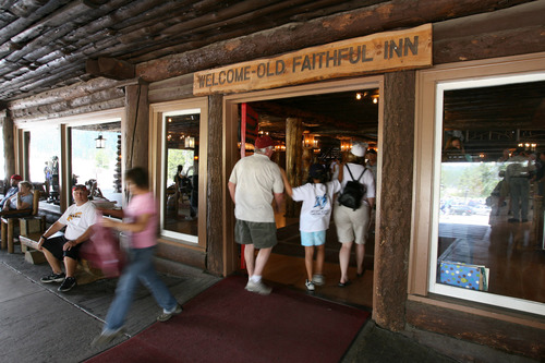 A family walking through the front door of the Inn underneath sign that says, "Welcome - Old Faithful Inn."