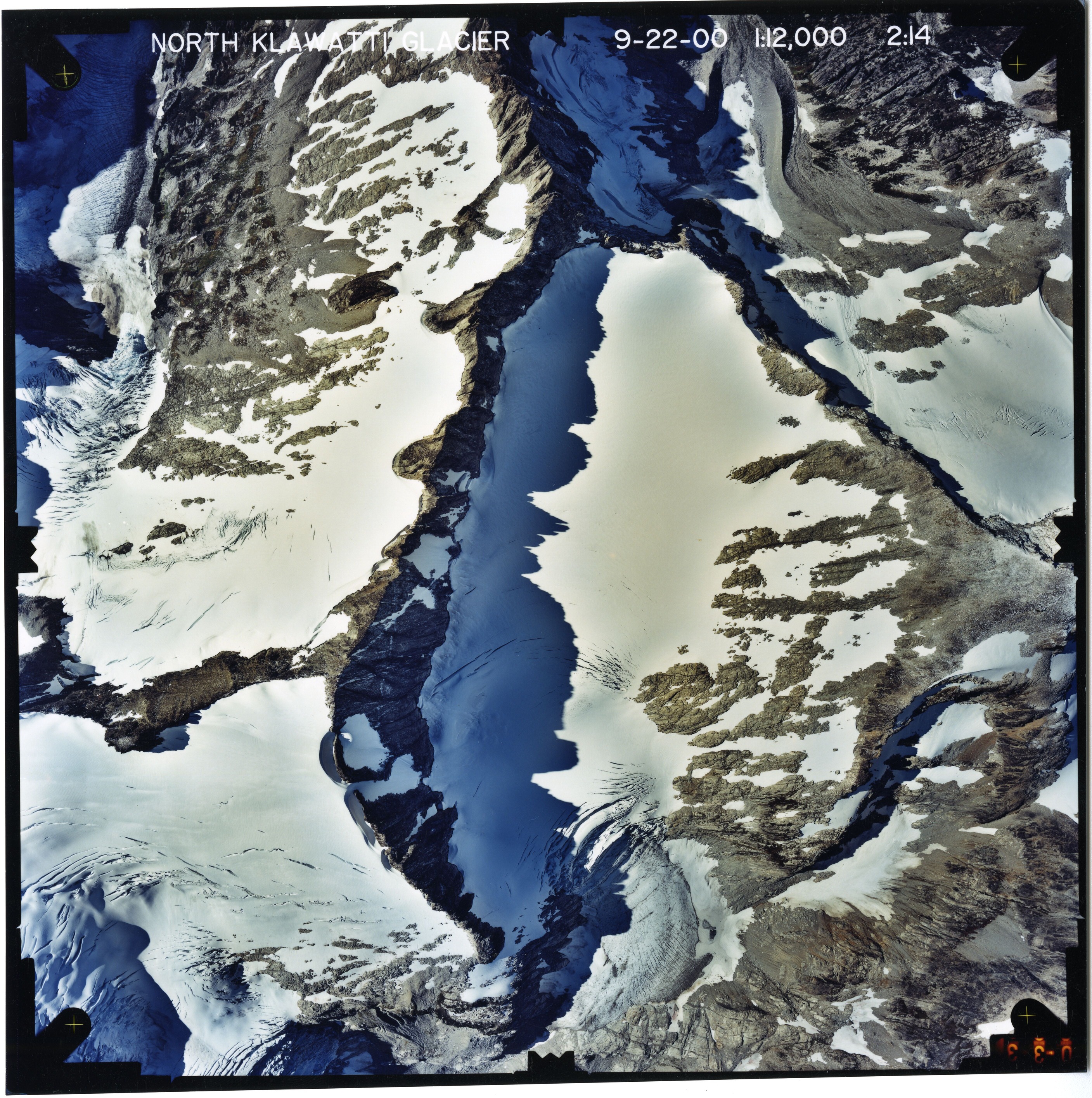 Color aerial photograph of glacier and snowfields on mountain peak.