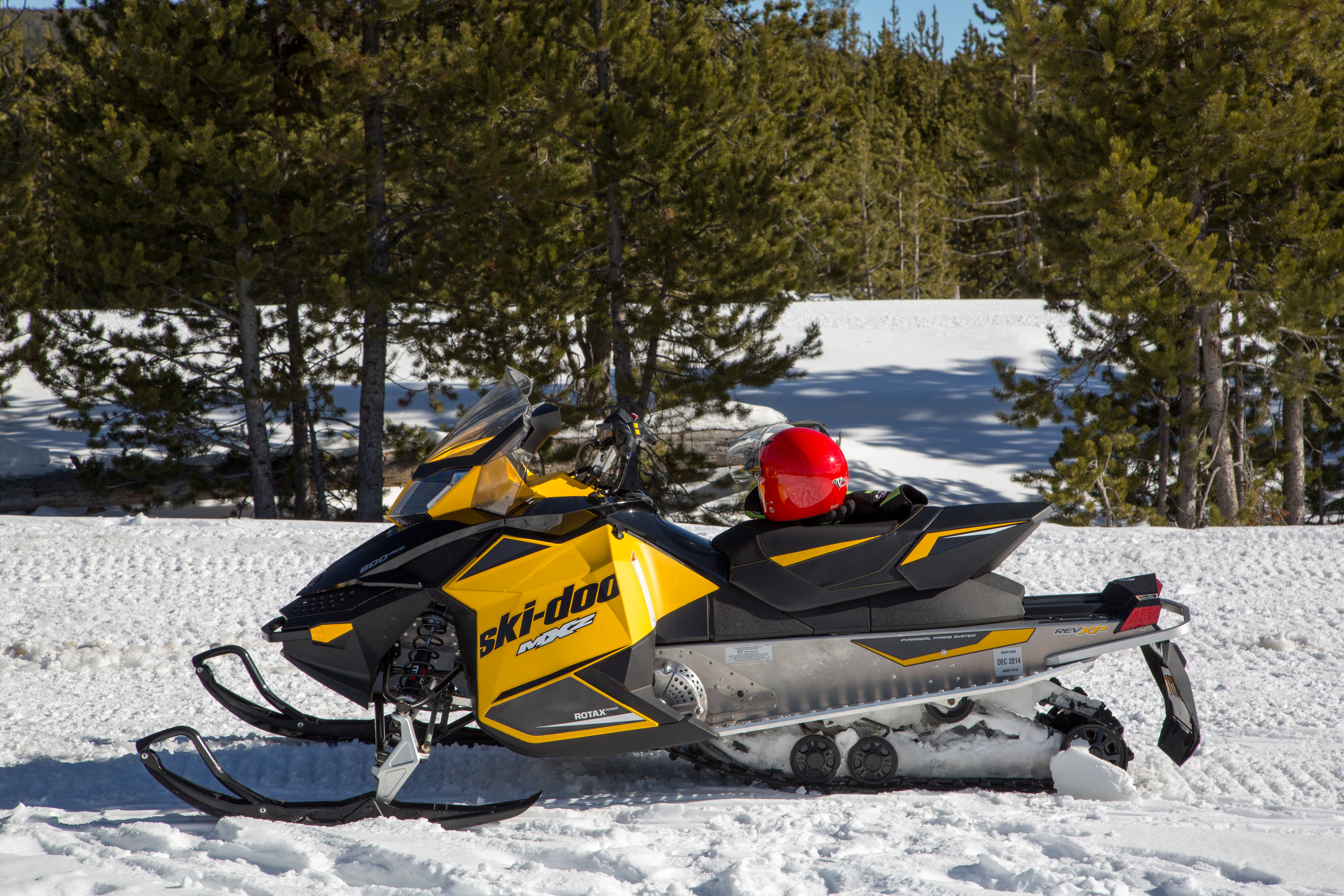 A black and yellow Ski-doo brand snowmobile is parked by itself 