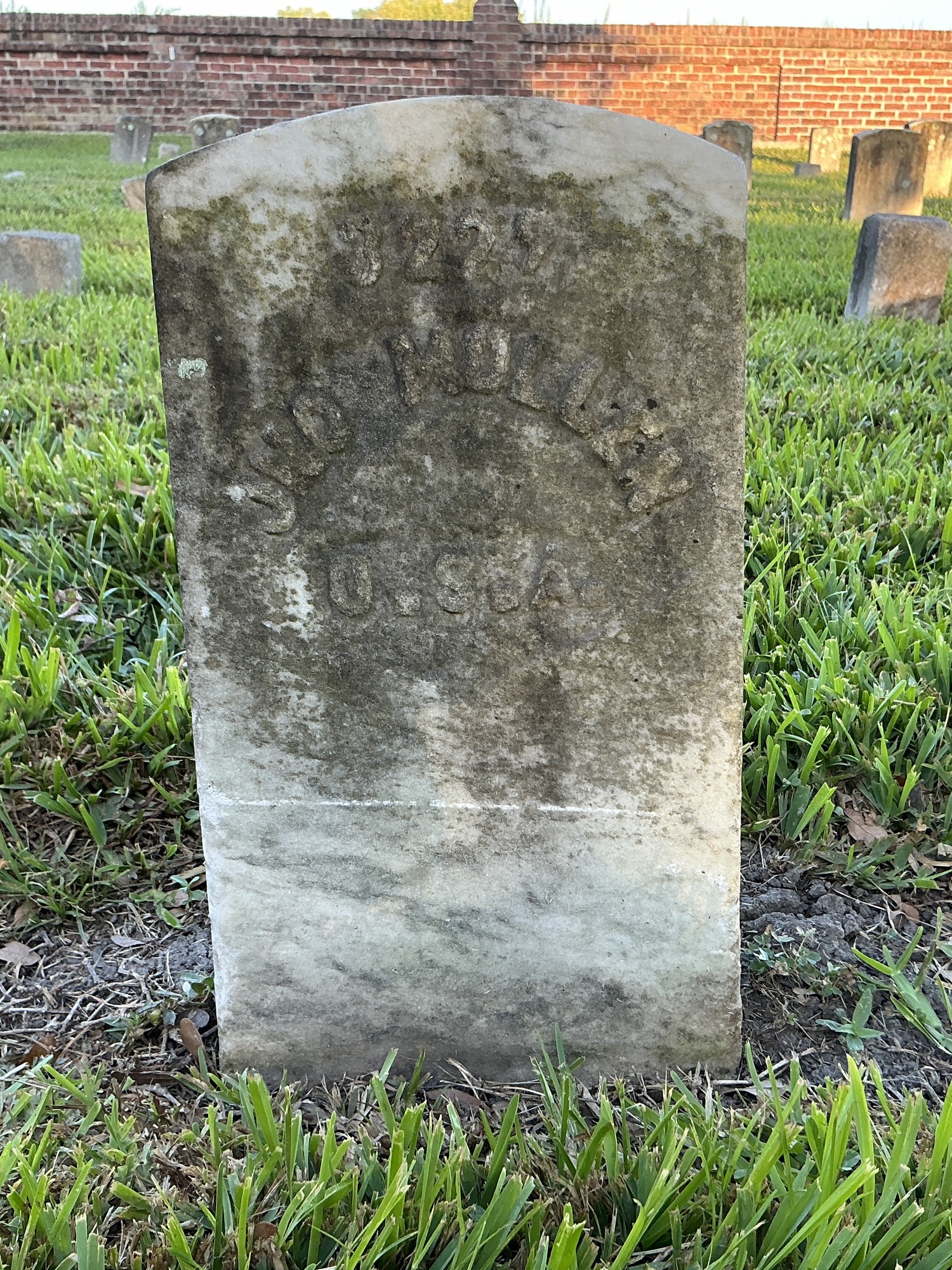 Front of historic upright marble headstone with recessed shield face.