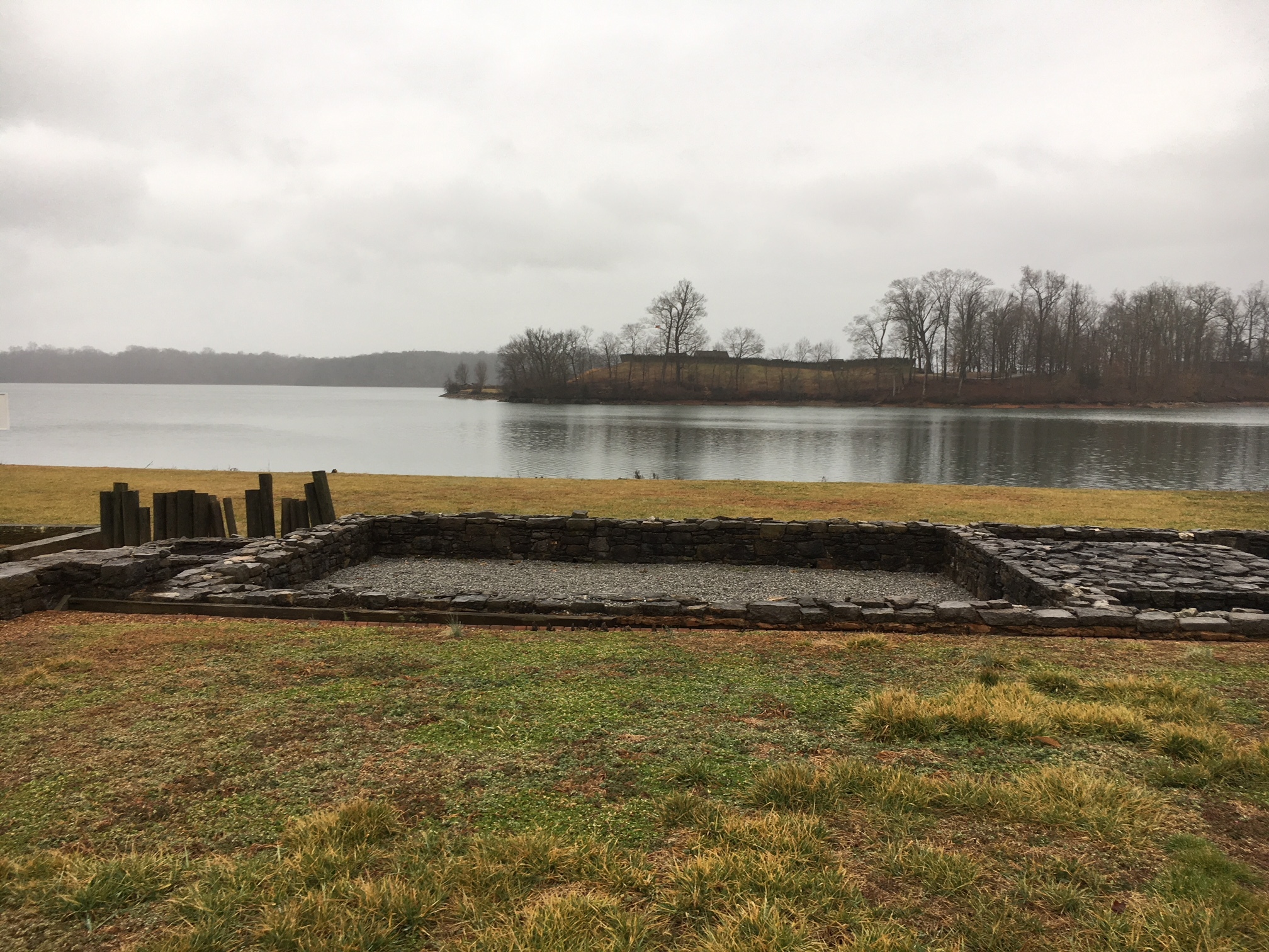 A large stone structure in front of a lake.