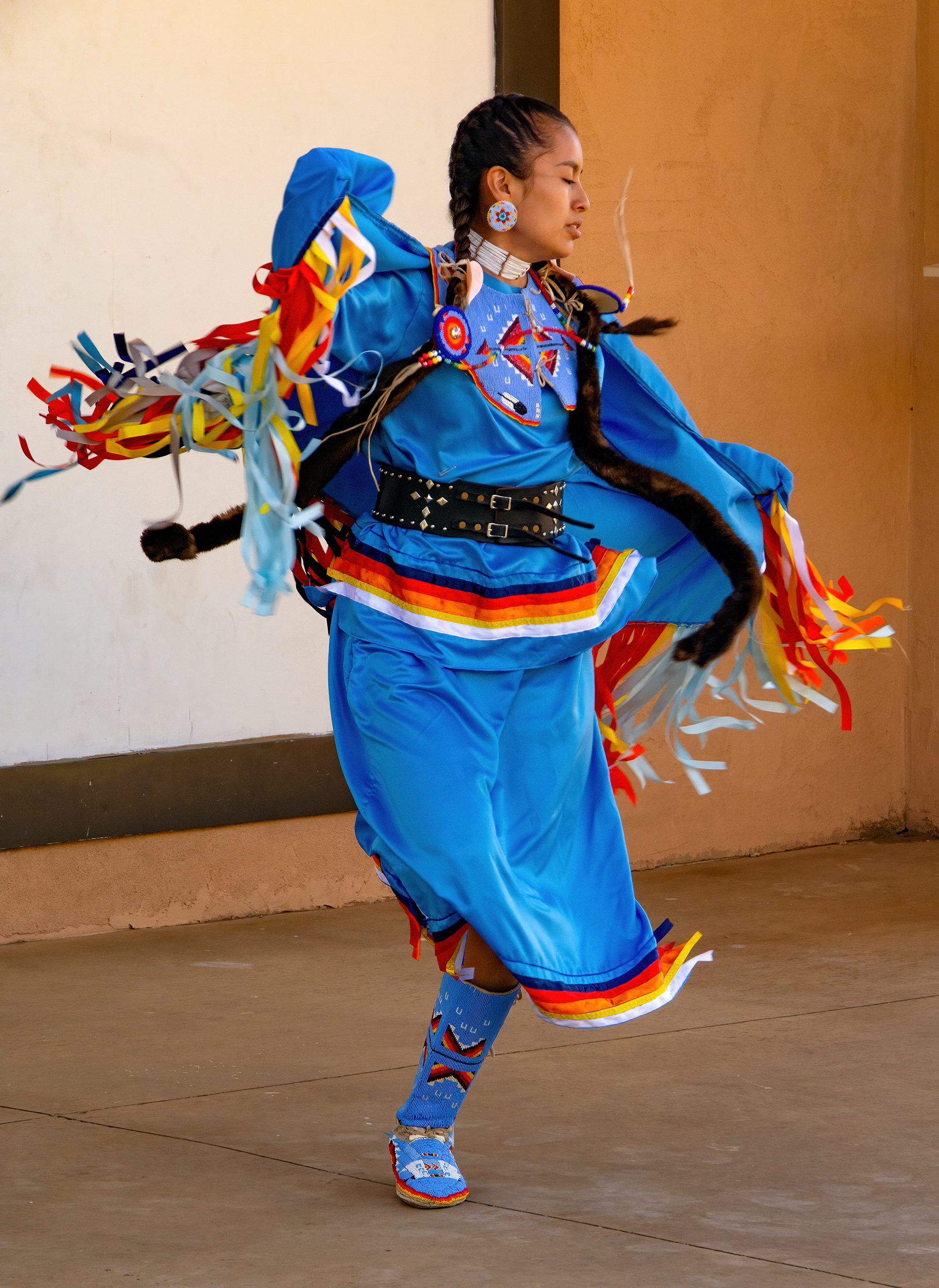 A Jicarilla Apache woman in colorful regalia dances at the Park Amphitheater.