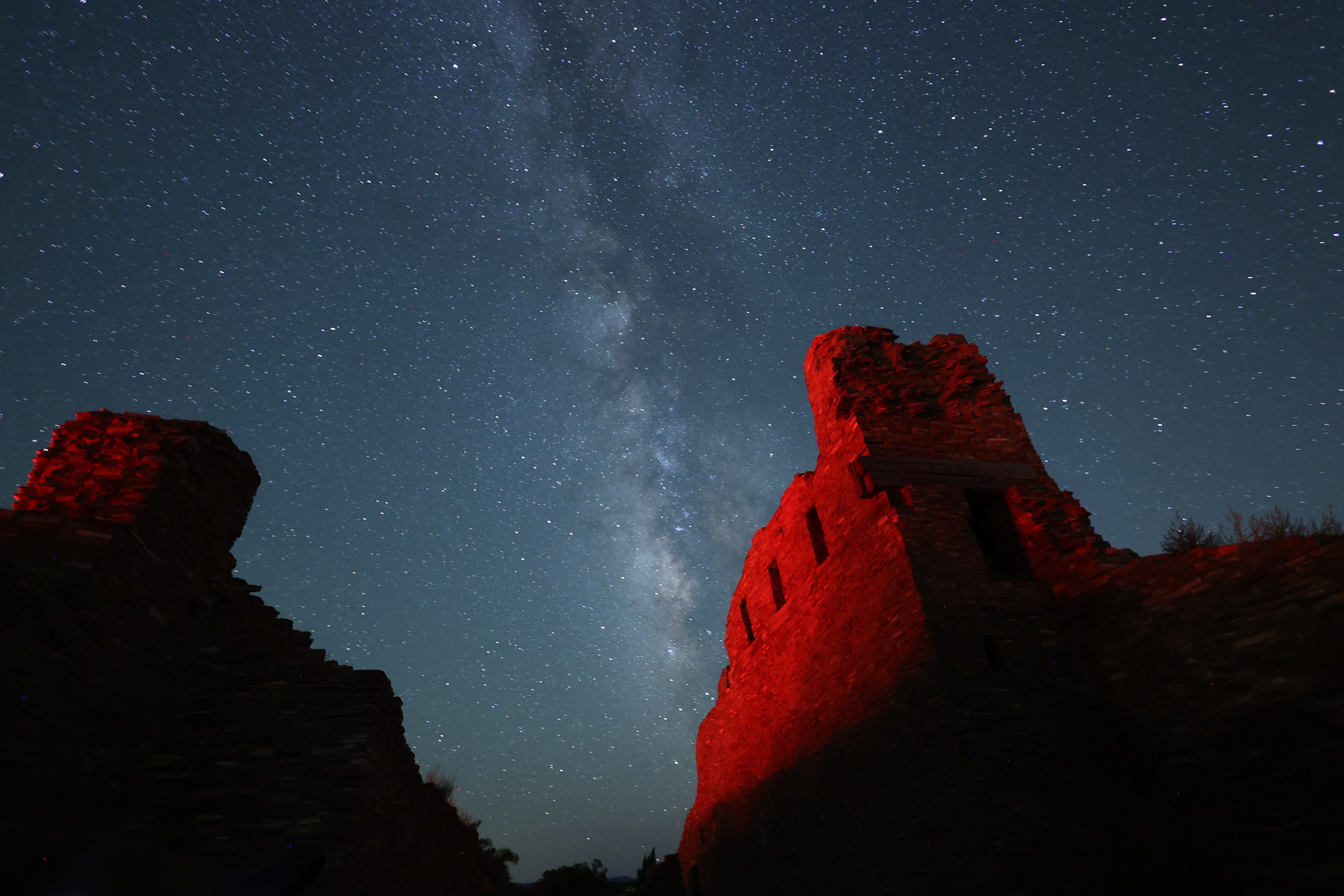 Milky Way in a starry sky with red sandstone church remnants in the foreground.