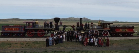 Visitors in period costume gather around the replica locomotives. 