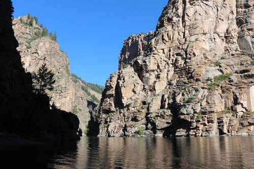 Steep canyon walls with water below them. One of the walls is completely in shadow.