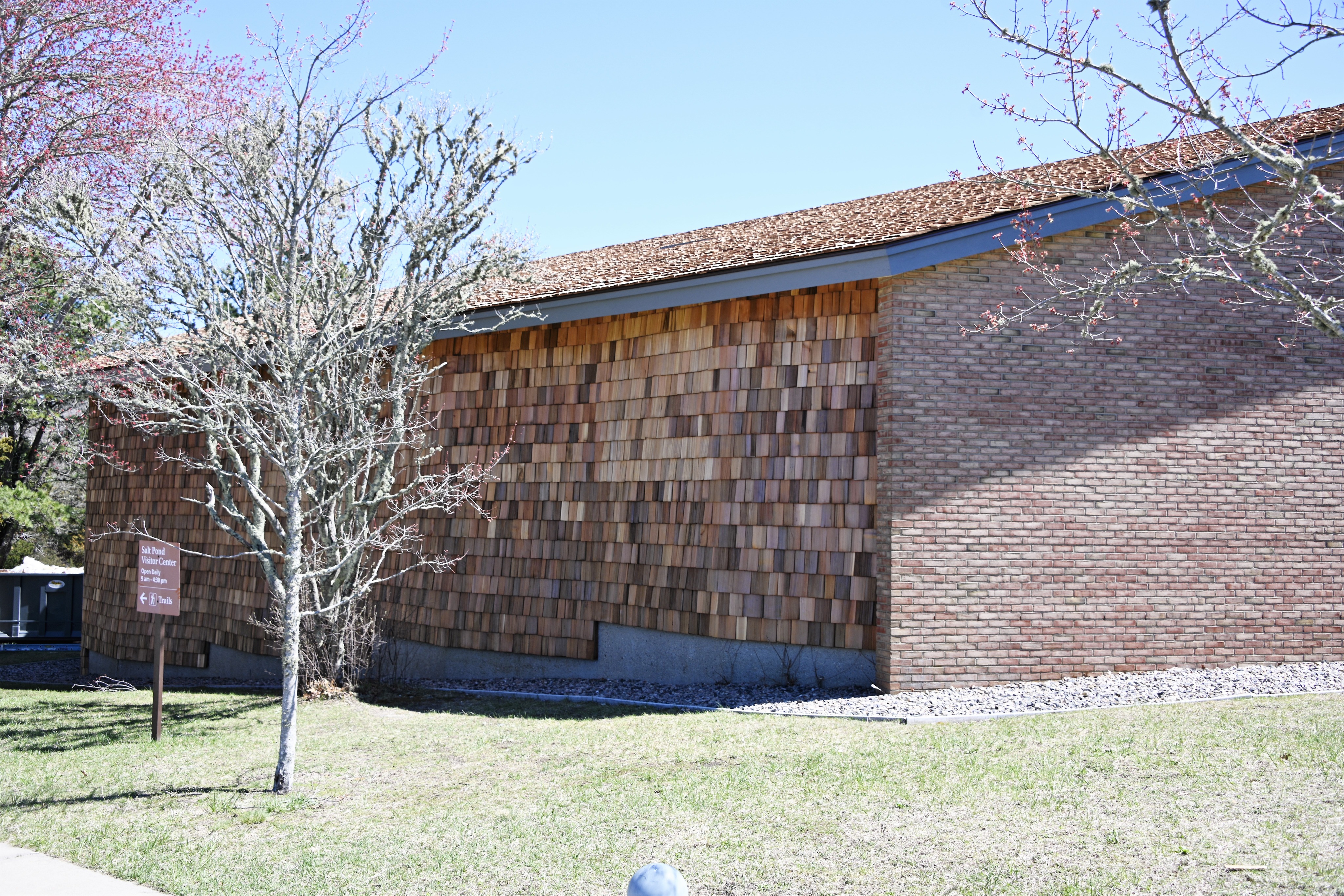 The side of a brick and wood shingle building that has been freshly repaired.